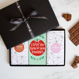 Three chocolate bars in a sleek black gift box tied by a Quirky-branded ribbon