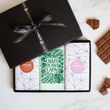 Three chocolate bars in a sleek black gift box tied by a Quirky-branded ribbon