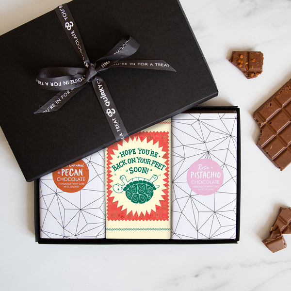 Three chocolate bars in a sleek black gift box tied by a Quirky-branded ribbon with the turtle design on the middle bar