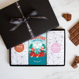 Three chocolate bars in a sleek black gift box tied by a Quirky-branded ribbon